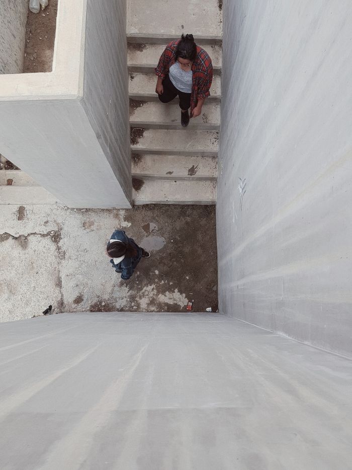 An overhead shot capturing a woman and a child walking down concrete stairs in an urban setting.