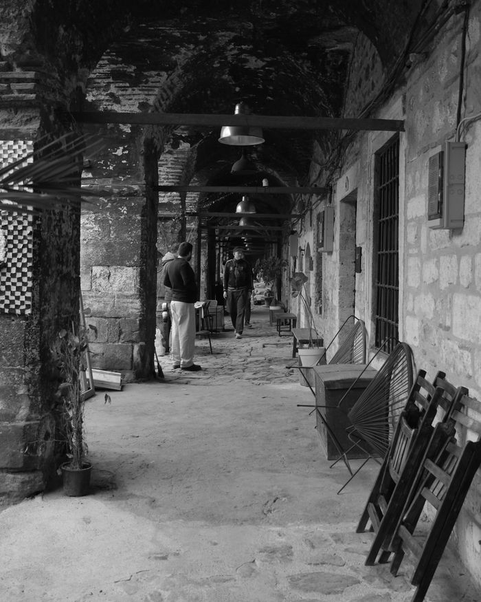 A historic covered corridor in İstanbul with arches and people walking.