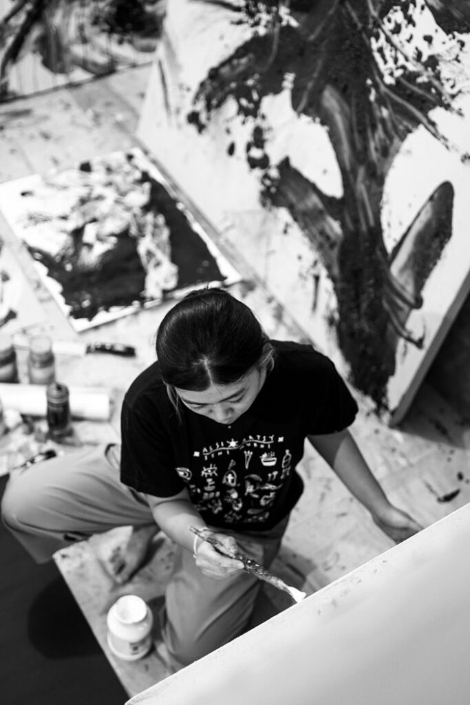 Artistic shot of a young woman painting abstract art in a studio.